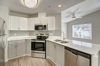 a kitchen with grey cabinets and stainless steel appliances